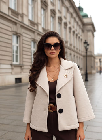 Manteau court beige avec boutons noirs et broche